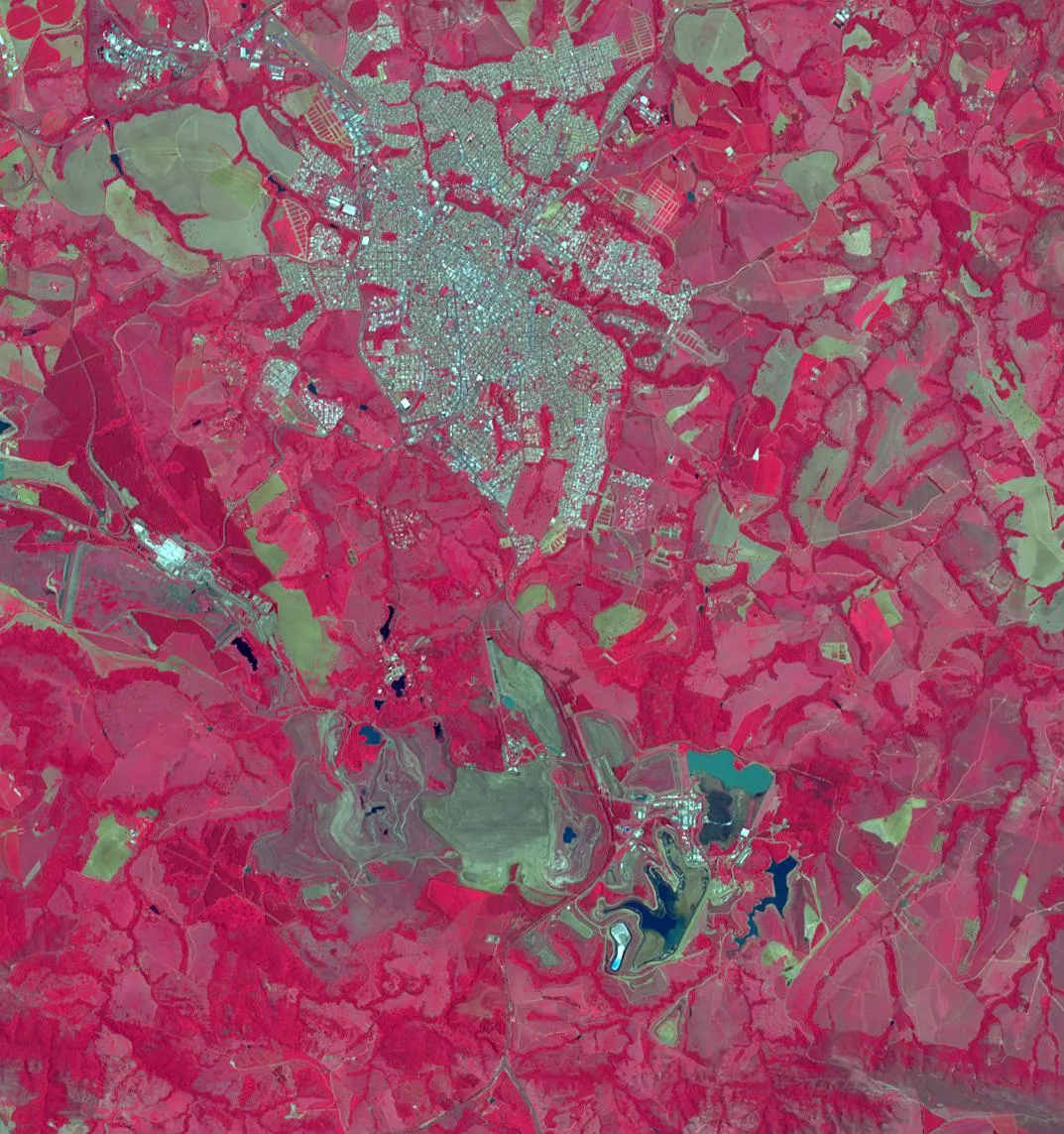 Imagem de satélite em cores falsas, com a vegetação em vermelho, a mancha urbana de Araxá no alto e, embaixo, cavas de mineração, áreas cinzentas e lagoas