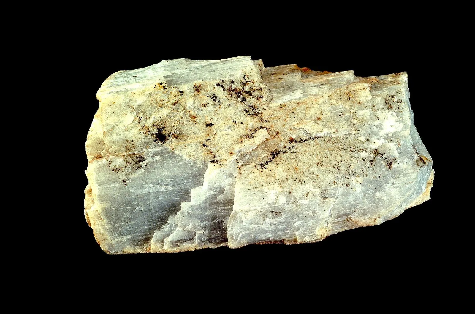 Bloco de espodumênio, mineral claro com faixas brancas, esverdeadas e bege, sobre fundo preto