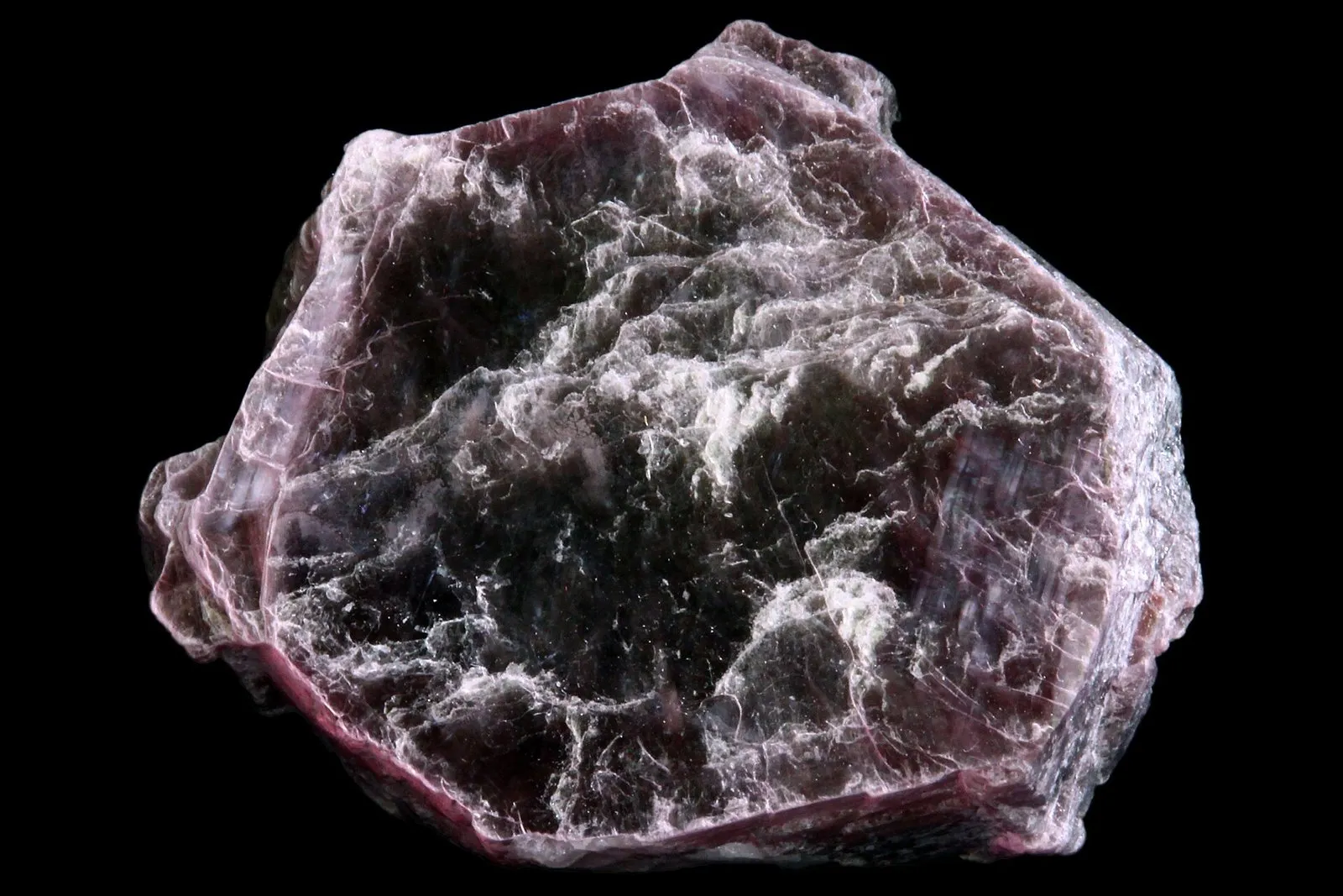 Pedaço de lepidolita, mineral em camadas finas e brilhantes, de cor lilás e cinza, sobre fundo preto